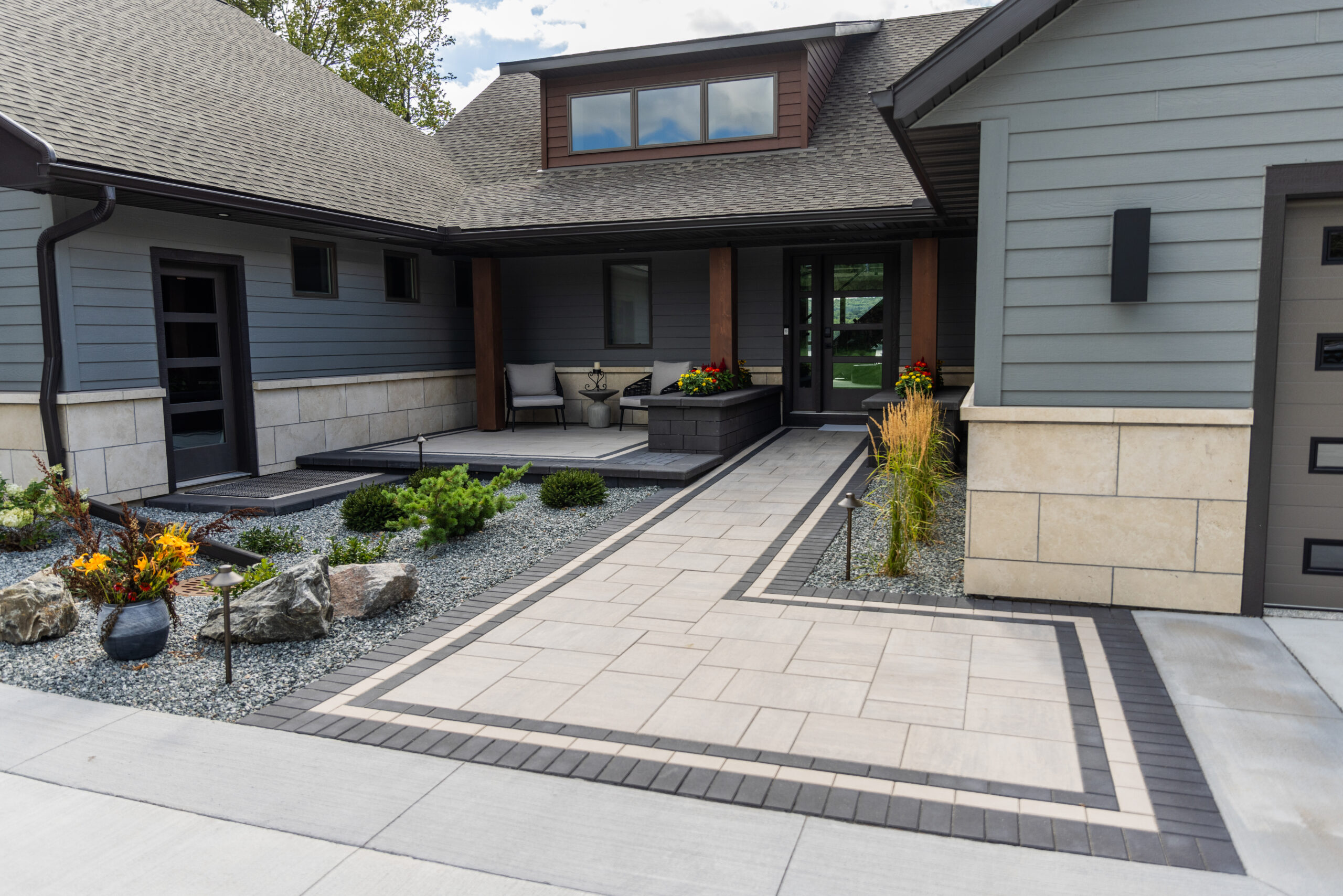 Elegant Front Paver Entry with Raised Patio & Built-In Planters – Hudson, WI Front paver entry with a raised seating area, built-in planters, and low-maintenance plantings at a Hudson, WI riverfront home.